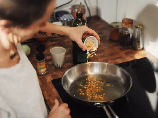 Adding spices to a pan on a gas stove