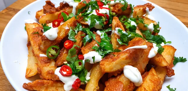 Masala chips topped with chillies, herbs and sauce