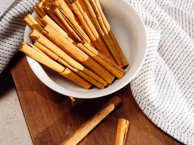Cinnamon sticks in a white bowl on a wooden board.