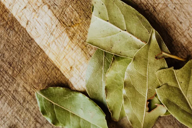 Dried bay leaves arranged on a wooden chopping board.