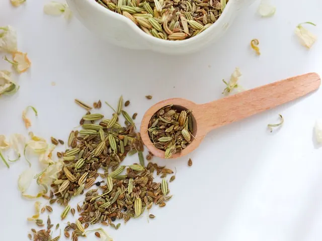 Fennel seeds in a bowl beside a wooden spoon.