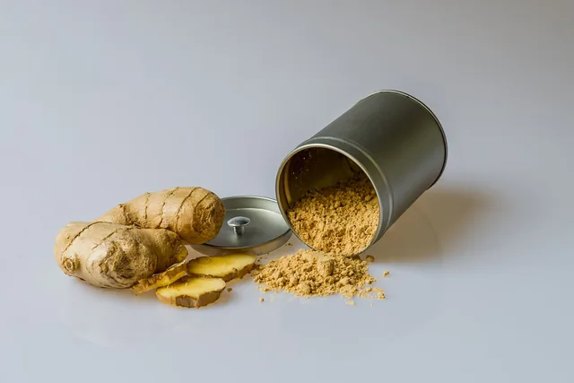 Fresh ginger, sliced ginger and ground ginger beside a metal container.