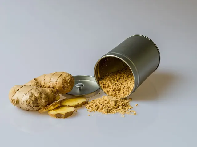 Fresh ginger, sliced ginger and ground ginger beside a metal container.