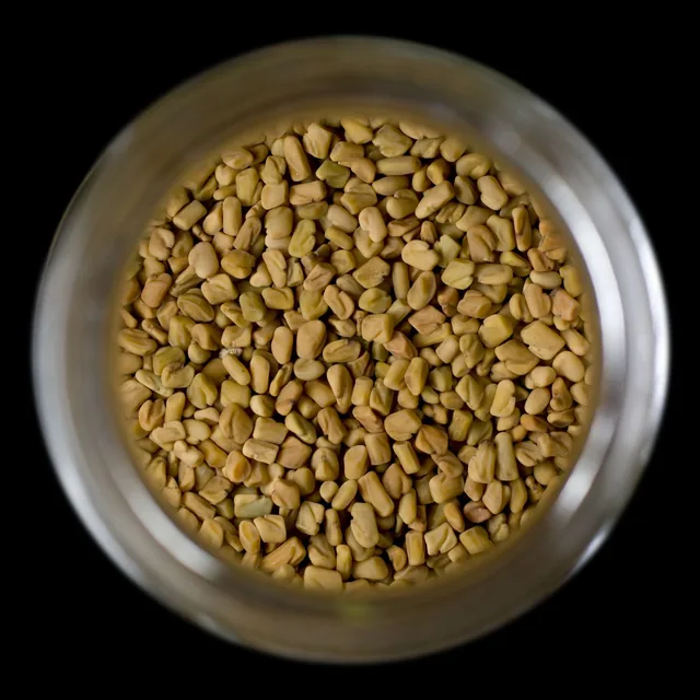 Golden fenugreek seeds viewed from above in a container.