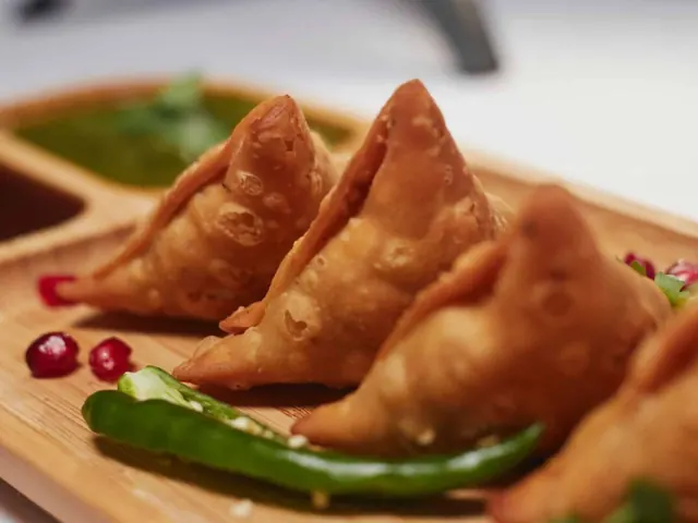 Golden fried samoosas with chillies and dipping sauce