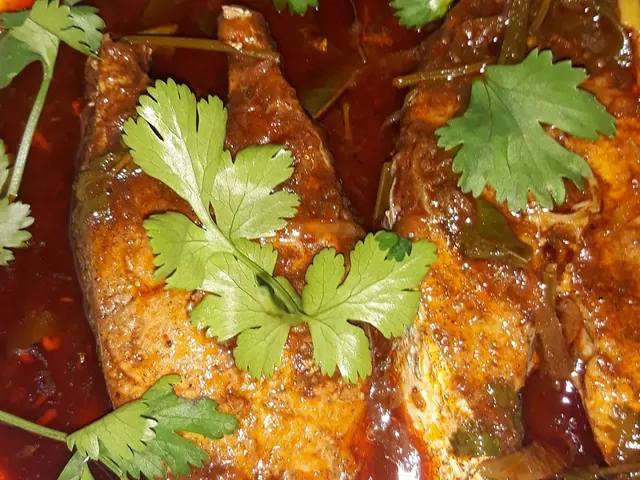 Jan Pillay’s fish curry in a red gravy, garnished with fresh dhania on a floral plate