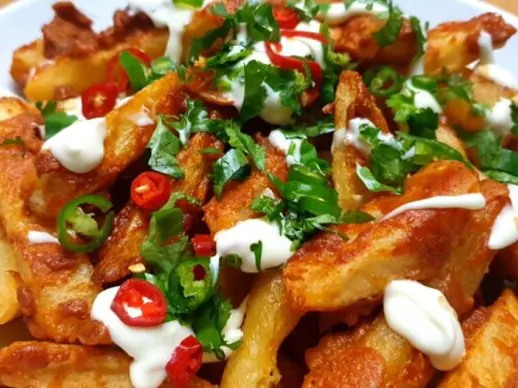 Masala chips topped with chillies, herbs and sauce