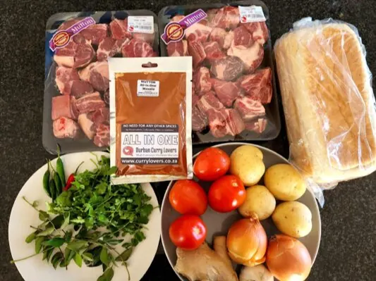 Mutton, potatoes, tomatoes, onions, masala and bread ready for bunny chow