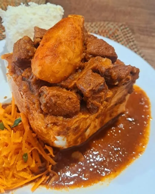 Pregan Moodley’s mutton bunny with potato, thick gravy and carrot salad on a white plate