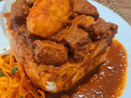 Pregan Moodley’s mutton bunny with potato, thick gravy and carrot salad on a white plate