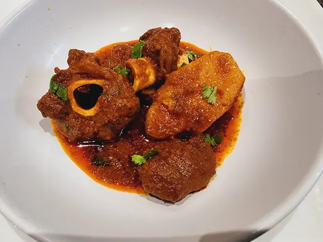 Shane’s mutton curry with bone-in meat, potato and fresh coriander on a white plate